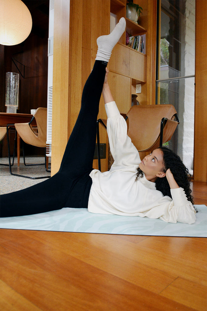 Girl half-laying on her side on top of the mat with kicking one leg upwards