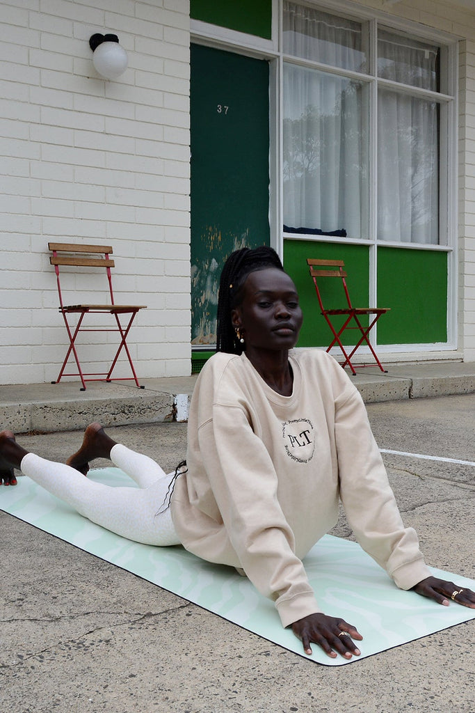 Girl half-laying on the mat with arms on the mat and shoulder up and backwards