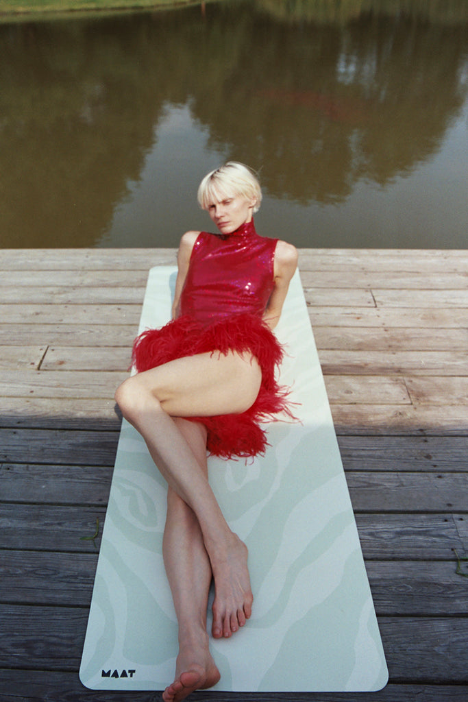 Girl laying the mat by the side of the pond