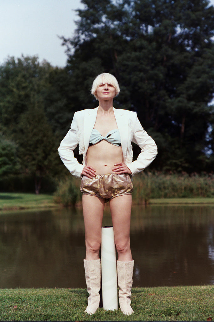 Girl standing by the side of the pond with mat roll standing between her tow legs