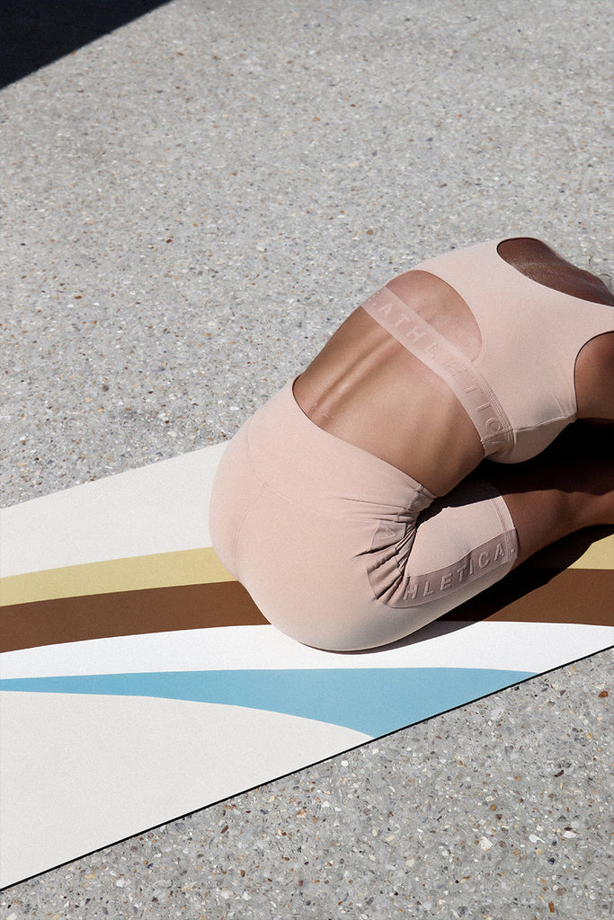 Girl sitting and bending towards the legs on the mat