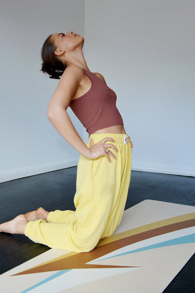 Girl kneeling on the mat with hands on the waist and neck and head bending backwards