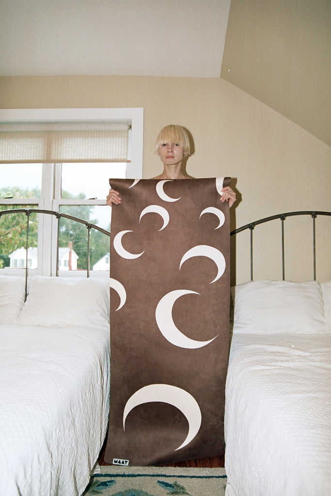 Girl holding flatlay mat standing between two beds