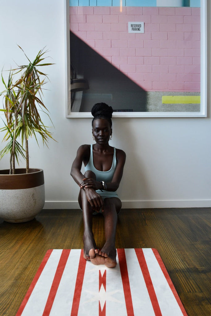 Girl sitting on the floor with foot on the edge of the mat