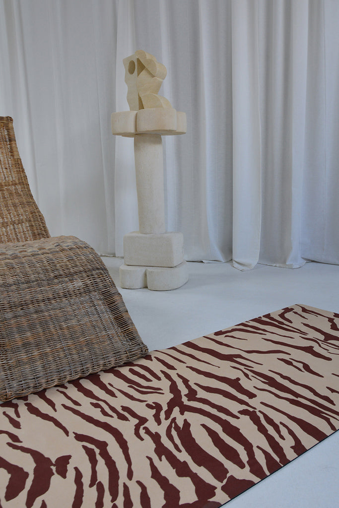 Yoga mat on a white floor next to a woven chair and sculpture