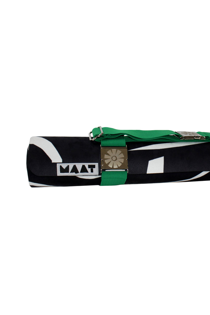 Green strap around black and white rolled yoga mat with 'MAAT' branding on a white background