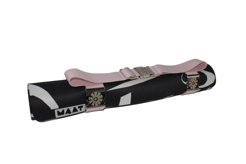 Pink yoga mat strap around a black and white mat